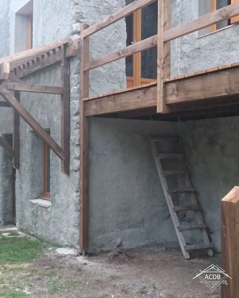 Escalier extérieur en douglas ancré dans le mur en moellons