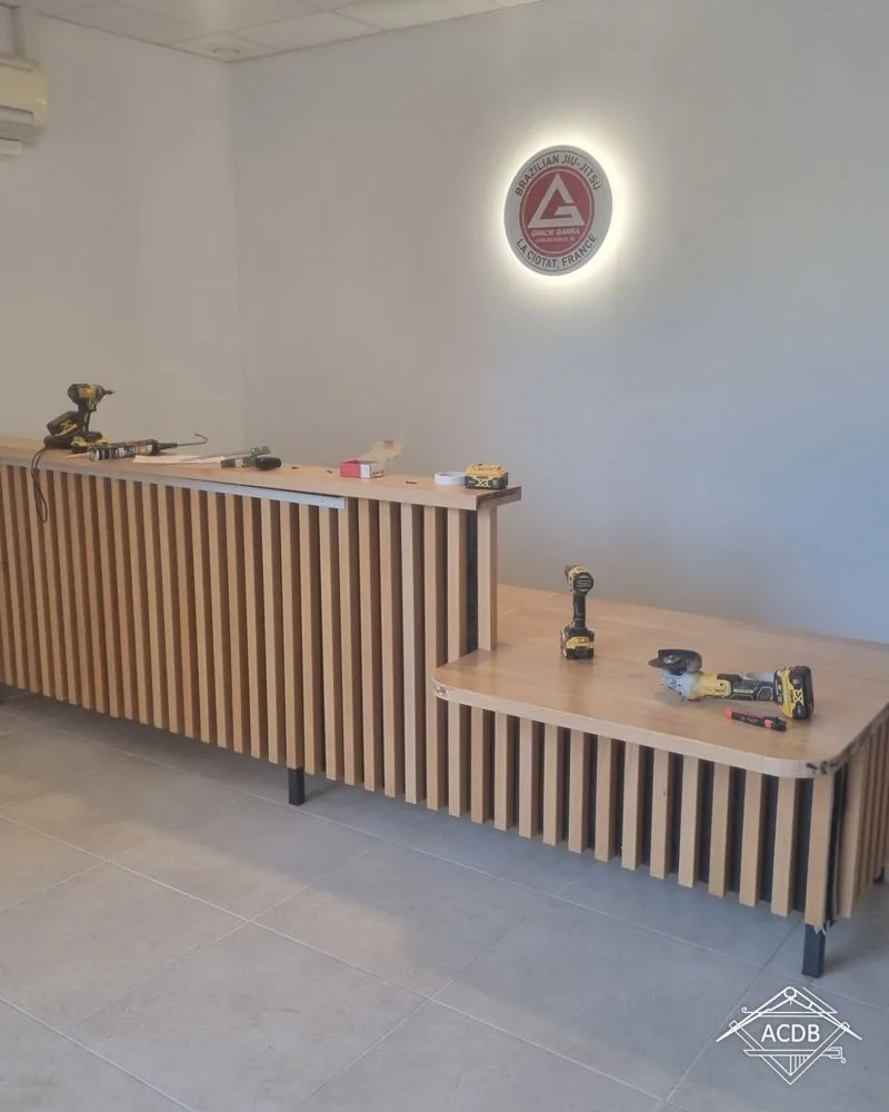 Comptoir d'accueil en hêtre terminé sous le logo du club de jiu-jitsu, La Ciotat
