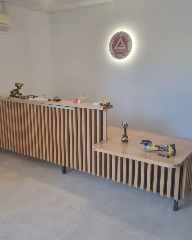Comptoir d'accueil en hêtre terminé sous le logo du club de jiu-jitsu, La Ciotat